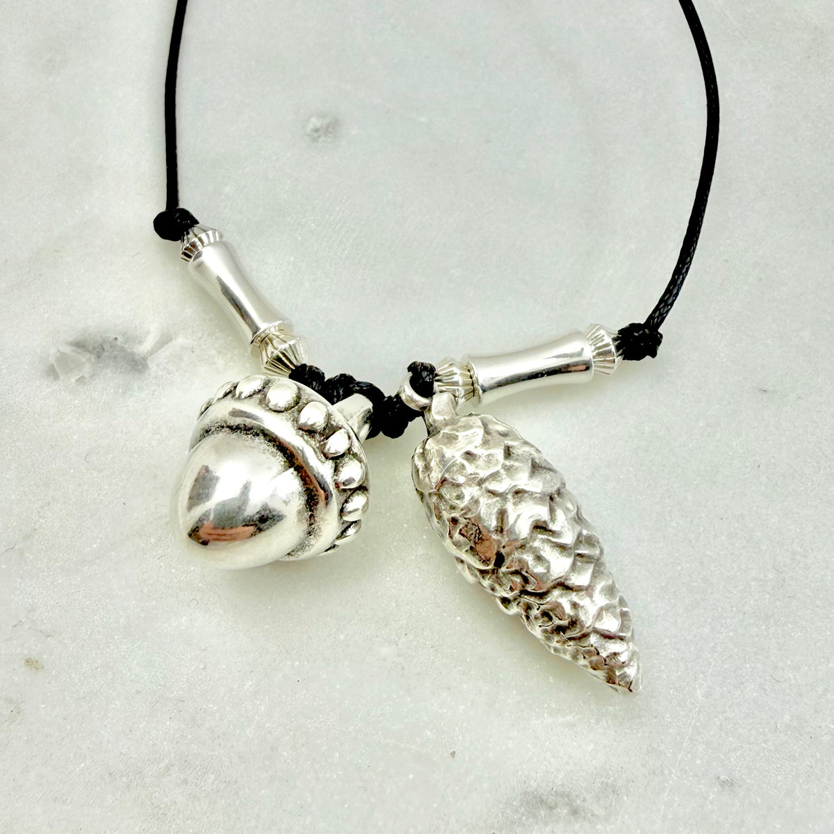 silver pendant necklace: με black cord με δύο silver-tone charms: ένα βελανίδι και ένα κουκουνάρι, σύμβολα της φύσης και του φθινοπώρου